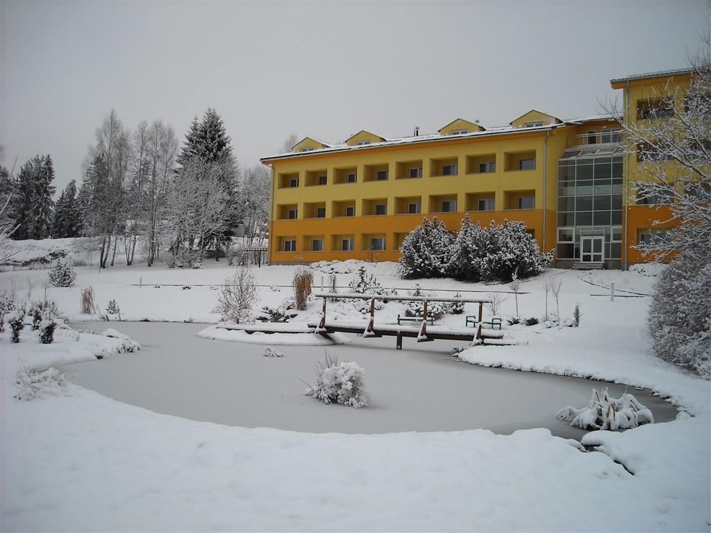 Zimní pohled na hotel Frymburk přes jezírko.