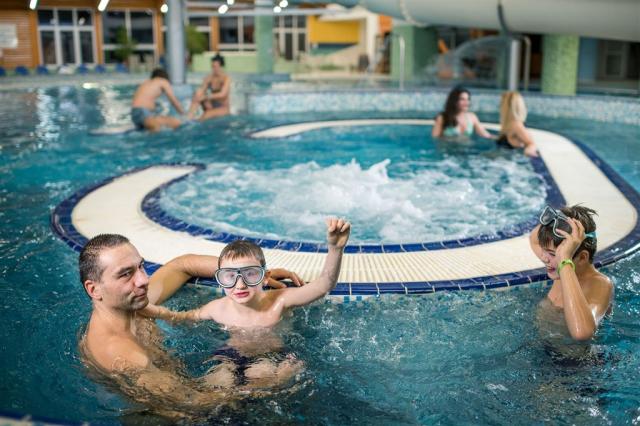 Pohled na rodinu hrající si ve vnitřním aquaparku hotelu Frymbu