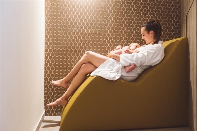 Žena kojící malé dítě v klidné zóně wellness.