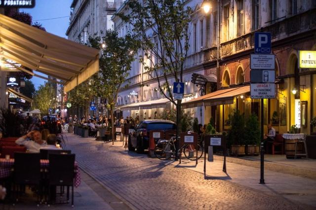 Letní večer poblíž Piotrkowska. Rušná dlážděná ulice, listnaté 