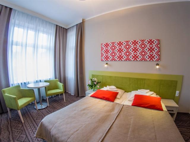 Pohled na manželskou postel v pokoji hotelu NAT