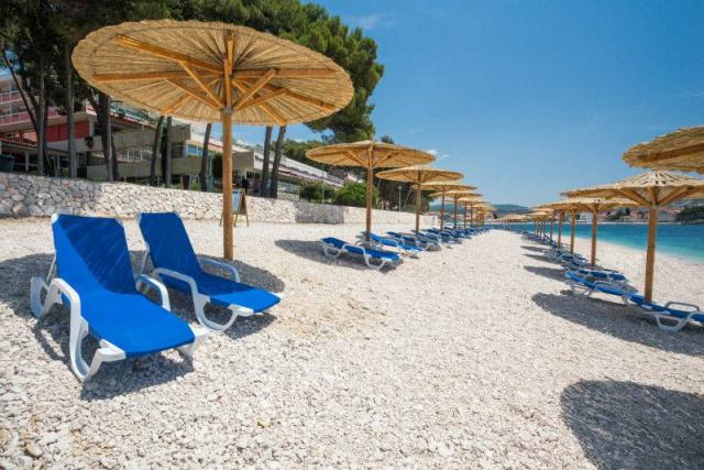 Primošten - pláž před hotelem Zora, slunečníky, lehátka.