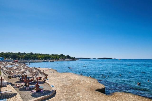 Hotel Delfin Plava Laguna - pláž betonová plata, slunečníky, mo