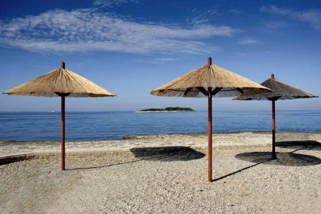 Hotel Delfin Plava Laguna - oblázková pláž se slunečníky.