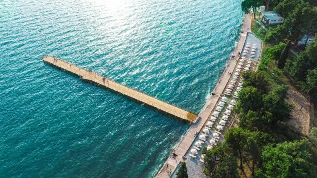 Pláž s lehátky a slunečníky a molo.