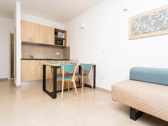 Apartmány Medena - kuchyňský kout, jídelní stůl a gauč.